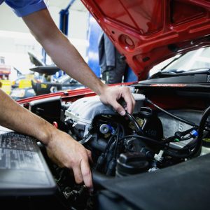 AE8XYW Close up of male auto mechanic working on engine in auto repair shop