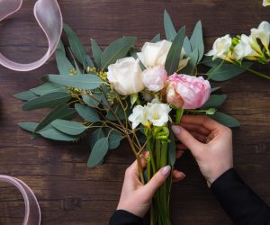 Florist at work: woman making fashion modern bouquet of different flowers on wooden background. Masterclass. Gift for bride on wedding, mother's, woman's day. Romantic spring fashion. Innocence tender.