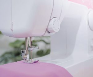 Close up of sewing machine working with purple fabric,  stitch new clothing.