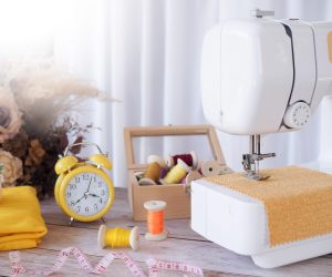 Close up sewing machine working with yellow fabric, sewing accessories on the table, stitch new clothing.