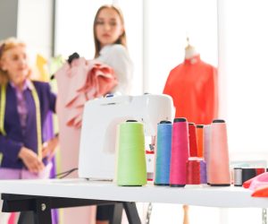 Fashion designer studio measuring textile material scissors cutting fabric by senior woman designer stylish showroom hanging clothes sewing machine and crafting tools designer working professional